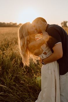 a man and woman kissing in the middle of a wheat field at sunset or sunrise