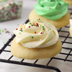 some cupcakes are on a cooling rack with frosting and sprinkles