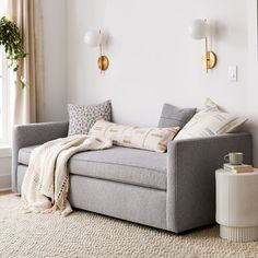 a living room with a gray couch and white rug on top of the floor next to a window