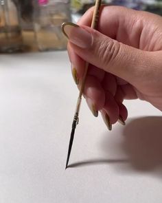 a person holding a pencil and pointing it at the tip of their fingernails