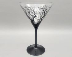 a black and white wine glass with trees painted on the side, in front of a gray background