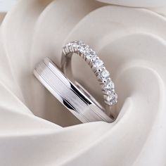 a white gold wedding band with three diamonds on top and in the middle, surrounded by swirling fabric