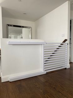 an empty room with wood floors and a white wall that has slats on it