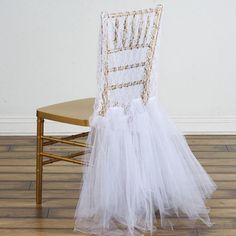 a chair with a white tulle skirt on it's back sitting in front of a wall