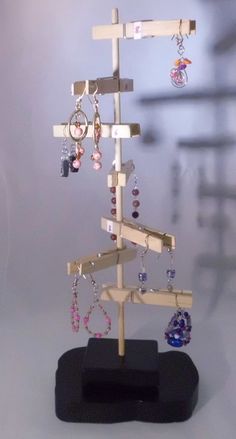 a small wooden tree with earrings hanging from it's sides on a black stand