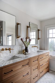 a bathroom with marble counter tops and double sinks in front of two mirrors on the wall