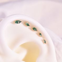 a pair of green earrings sitting on top of a white object