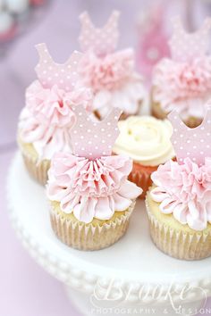 cupcakes decorated with pink and white icing on a cake platter for a princess themed birthday party