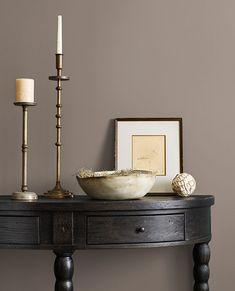 a wooden table with a bowl and two candles on it next to a framed photograph