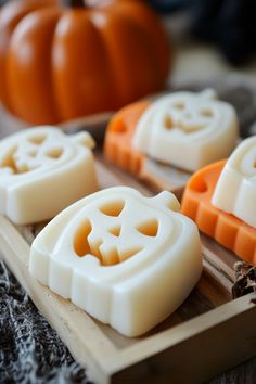 some white and orange soaps sitting on a wooden tray with pumpkins in the background