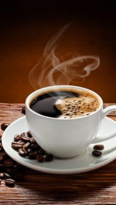 a cup of coffee with steam rising out of it on a saucer surrounded by coffee beans