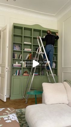 a man standing on a ladder in front of a bookshelf with green shelves