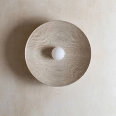 a white light fixture mounted on the side of a wall with a circular pattern around it