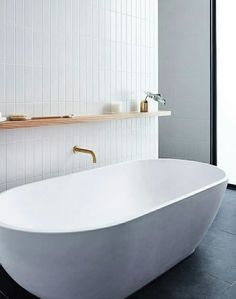 a white bath tub sitting in a bathroom next to a window