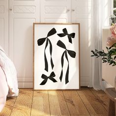 a black and white art piece sitting on top of a wooden floor next to a bed