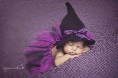 a newborn baby wearing a witches hat and purple tutule sleeping on a blanket