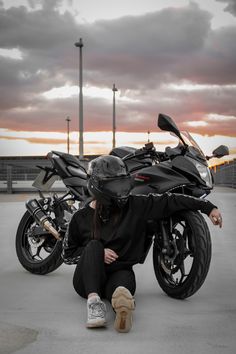 a woman sitting on the ground next to two parked motorcycles