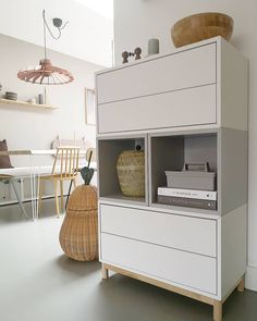 a white cabinet sitting in the middle of a room next to a table and chairs