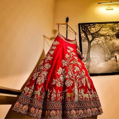 a red and gold dress hanging on a wall next to a framed photograph in a room