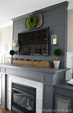 a fireplace with a tv above it and some plants on the mantels in front of it