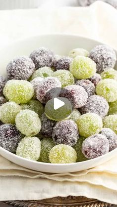 a white bowl filled with powdered sugar covered donuts on top of a table