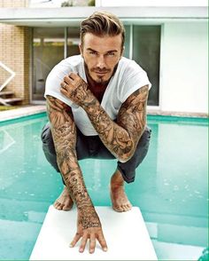 a man with tattoos on his arms leaning over a pool