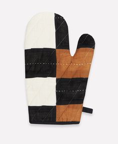 an oven mitt made out of black, white and brown fabric with stitching