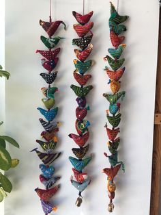 several colorful birds hanging from strings on a wall