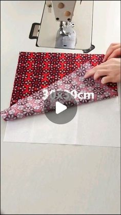 someone is cutting fabric on top of a table with a sewing machine in the background