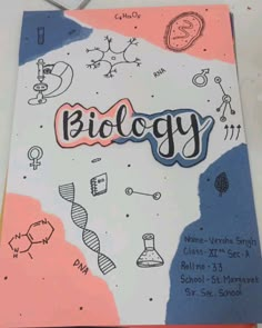 a notebook with the word biology written on it and doodles around it in pink, blue, and orange