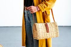 a woman carrying a wicker purse on her shoulder