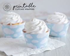 three cupcakes with white frosting in blue paper cups on top of a napkin