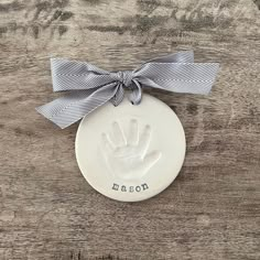 a ceramic ornament with a handprint on it and a ribbon tied around the top