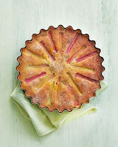 an apple pie with powdered sugar on top sitting on a green napkin next to it