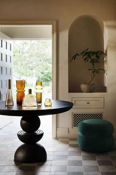 there is a table with bottles on it in the room next to a chair and window