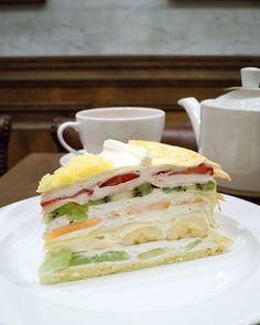 a white plate topped with a cut in half sandwich next to a cup and saucer