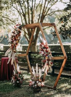 an outdoor ceremony setup with flowers and feathers on the arch, in front of a tree