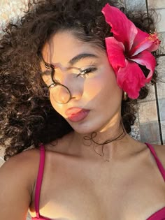 a woman with long curly hair and a flower in her hair is posing for the camera