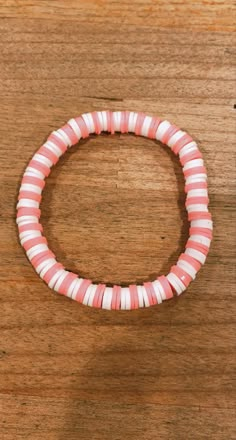 a pink and white beaded bracelet sitting on top of a wooden table