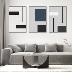 a modern living room with grey couches and art on the wall above it's coffee table