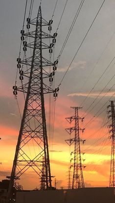 the sun is setting behind many power lines