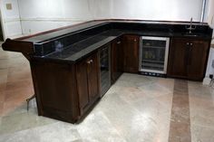 an empty kitchen with marble counter tops and dark wood cabinetry, along with stainless steel appliances