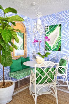 a living room with blue and green wallpaper, white furniture and a potted plant