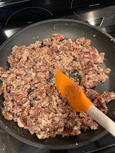 a frying pan filled with meat cooking on top of an electric stove burner