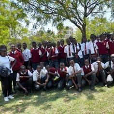 a group of young men standing next to each other in front of a large tree