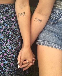 two people holding hands with tattoos on their arms and the words love written in small letters