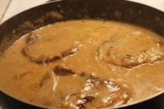 a pan filled with meat and gravy on top of a stove burner