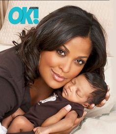 a woman laying on top of a bed holding a baby