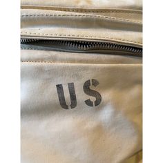 the back side of a white backpack with us on it's front pocket and zippered closures