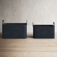 two black planters sitting on top of a hard wood floor next to a white wall